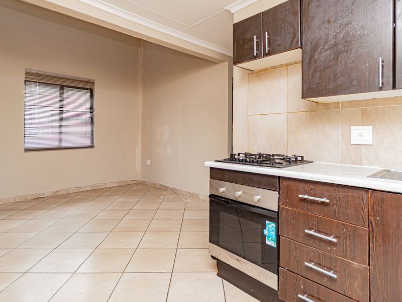 Open plan kitchen and living area featuring tiled flooring, dark wood cabinetry, built-in oven, gas hob, and neutral wall finishes.