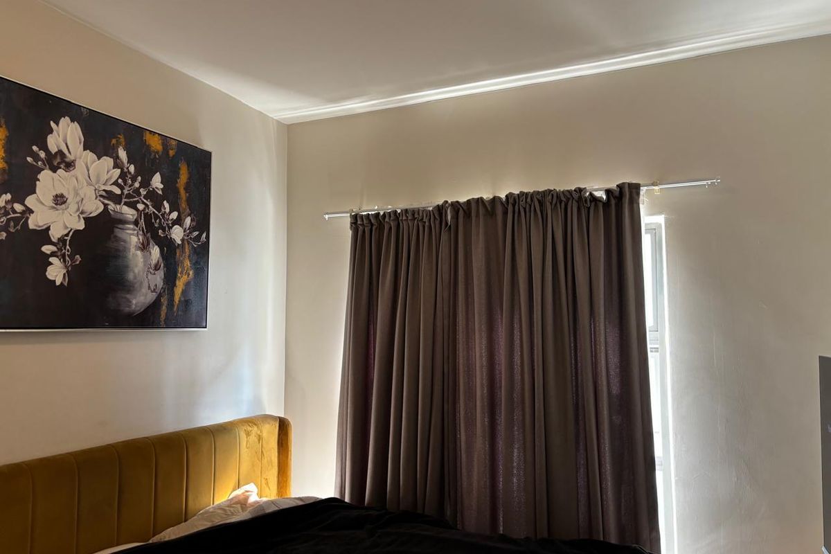 A well-maintained bedroom featuring crown molding and a curtain rod installed over the window area.