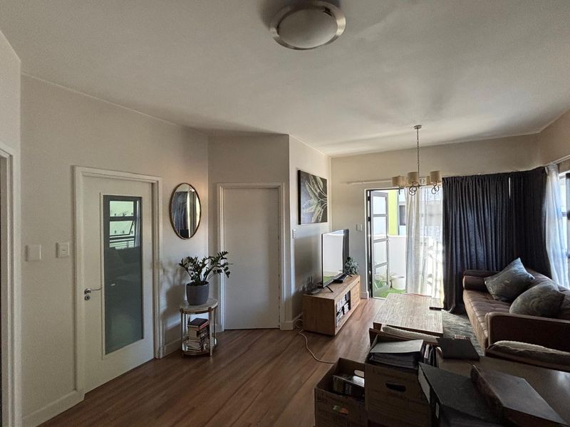 A comfortable living room featuring laminate flooring, a chandelier, and direct access to a balcony through a sliding glass door.
