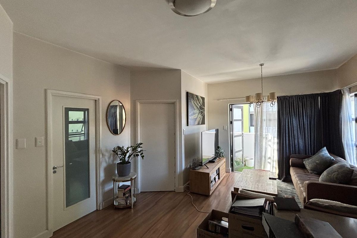 A comfortable living room featuring laminate flooring, a chandelier, and direct access to a balcony through a sliding glass door.