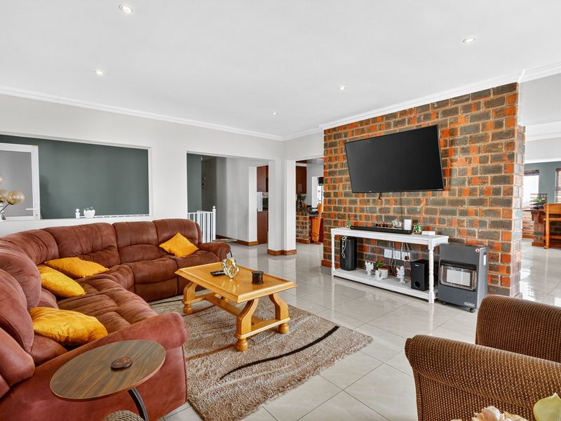 Spacious living room featuring a prominent exposed brick wall, neutral tiled flooring, and recessed lighting, creating a warm and inviting atmosphere.