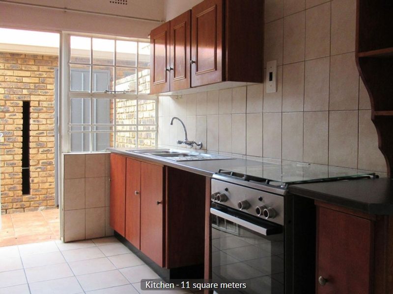 A functional kitchen featuring wooden cabinetry, tiled backsplash, and a freestanding stove, with direct access to an outdoor patio area.