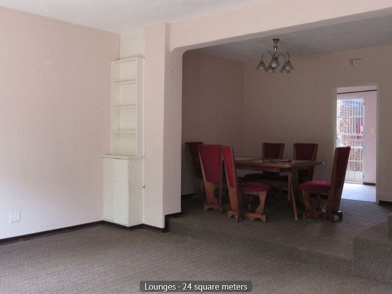 Open plan living and dining area featuring carpeted flooring, a built-in shelving unit, and a stepped transition between the two spaces.
