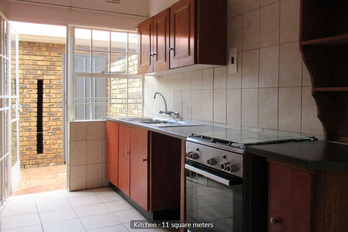 A functional kitchen featuring wooden cabinetry, tiled backsplash, and a freestanding stove, with direct access to an outdoor patio area.