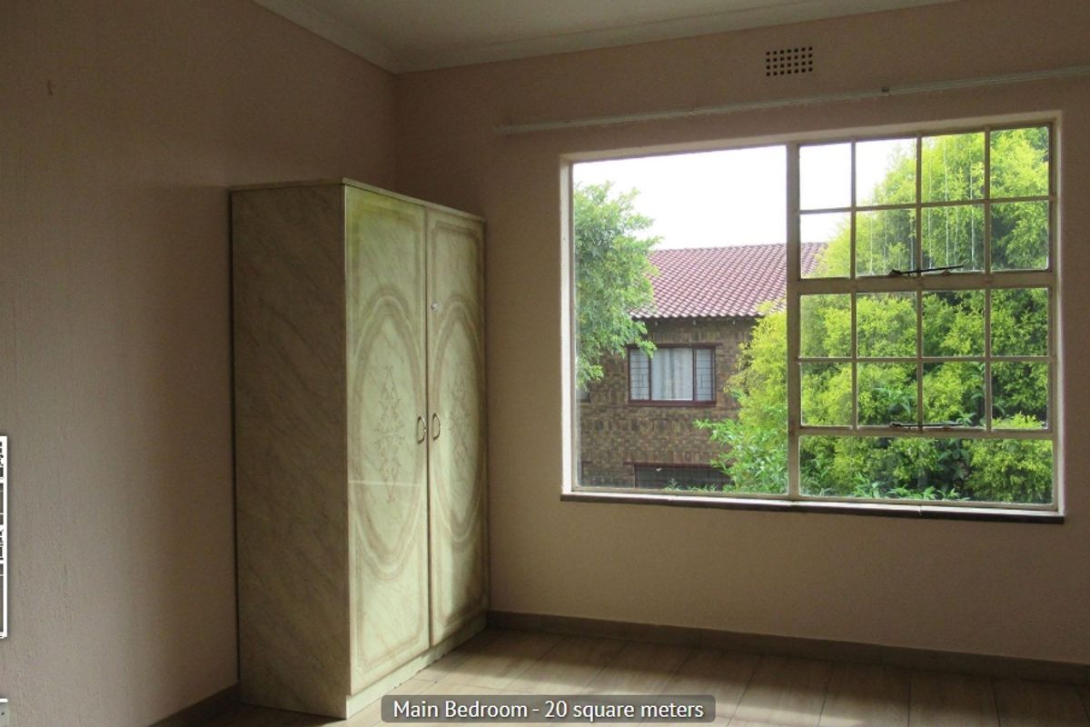 A bedroom featuring a large window providing natural light and a built-in cupboard for storage.