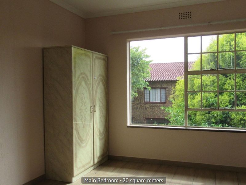 A bedroom featuring a large window providing natural light and a built-in cupboard for storage.