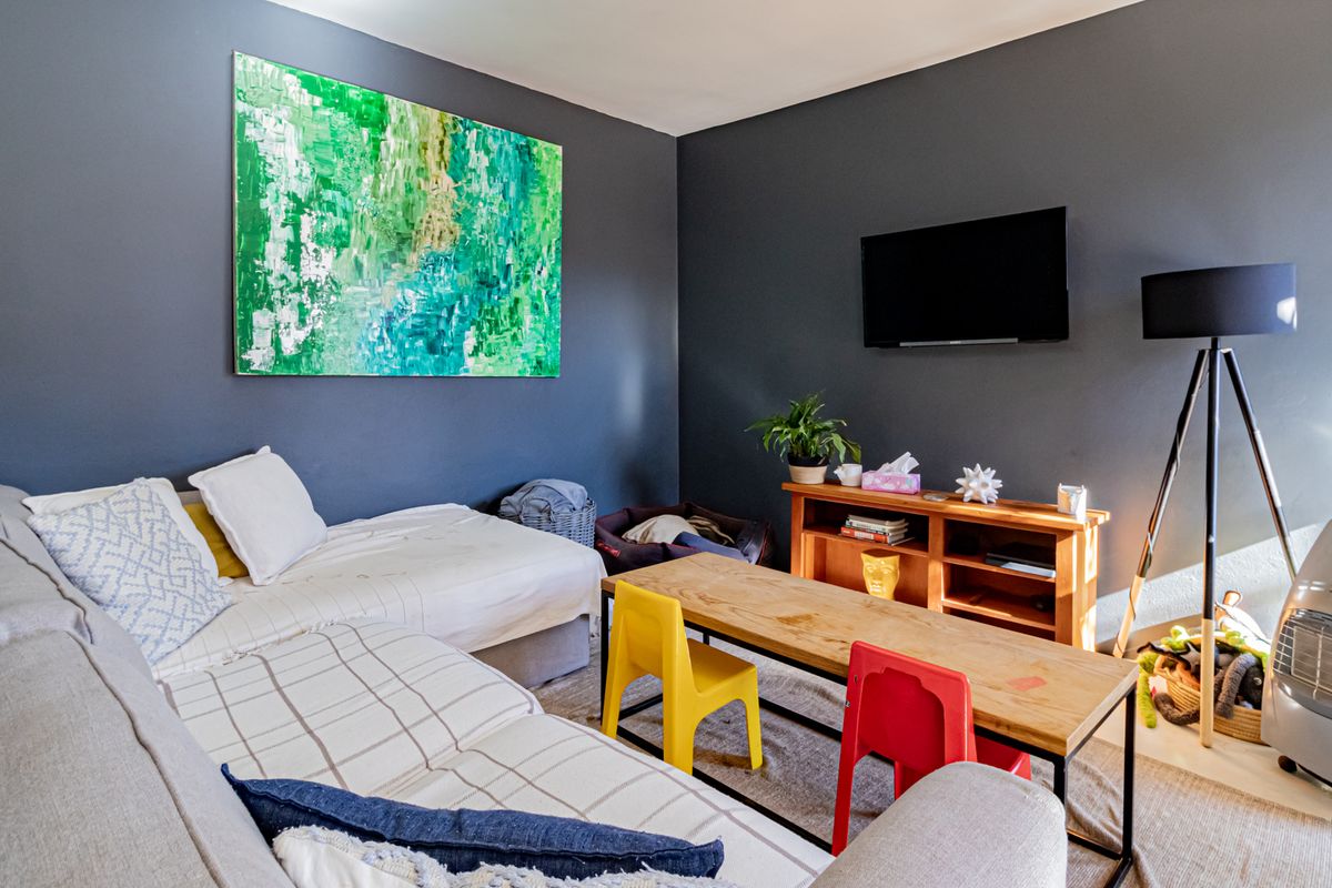 A living room featuring dark painted walls and a wall-mounted television, providing a functional space for relaxation and entertainment.
