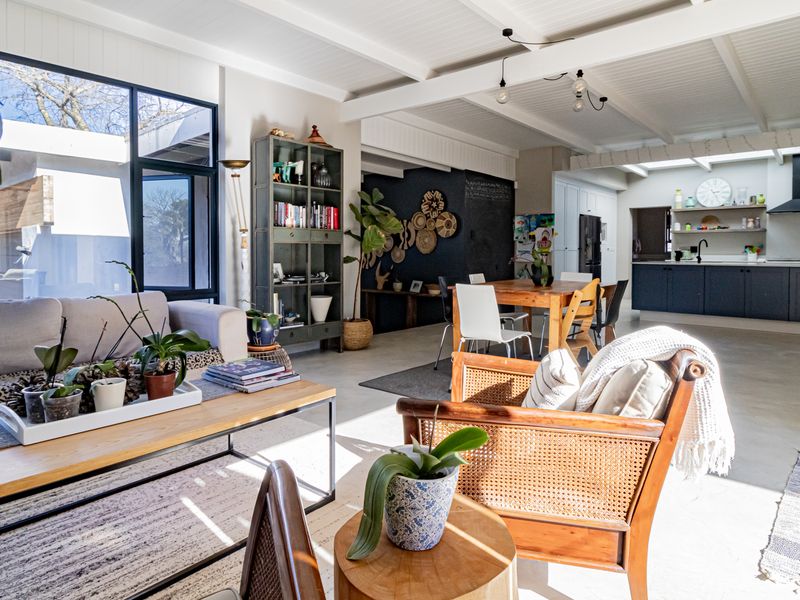 Spacious open-plan living and kitchen area featuring exposed beam ceilings, concrete floors, and large windows that provide abundant natural light.