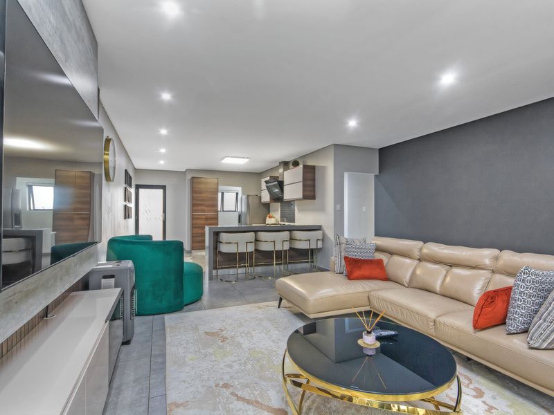Modern open-plan living area featuring a contemporary kitchen with an island, sleek cabinetry, and recessed lighting, seamlessly flowing into the lounge space.