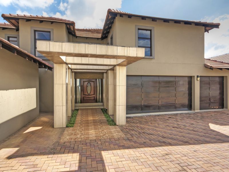 Modern double-storey residence featuring a paved driveway, double garage, and a prominent covered entrance portico with stone cladding details.