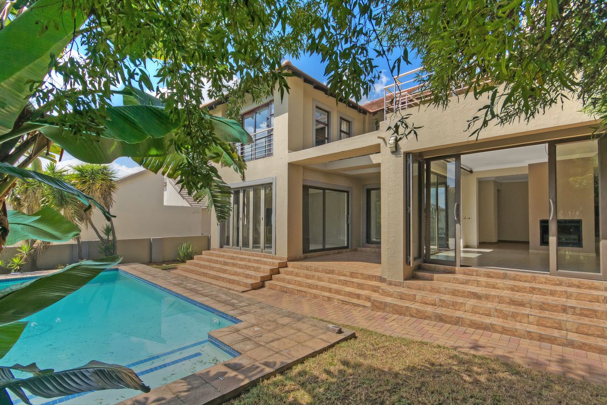 Rear view of the property featuring a swimming pool, paved patio area, and large sliding glass doors leading into the home.