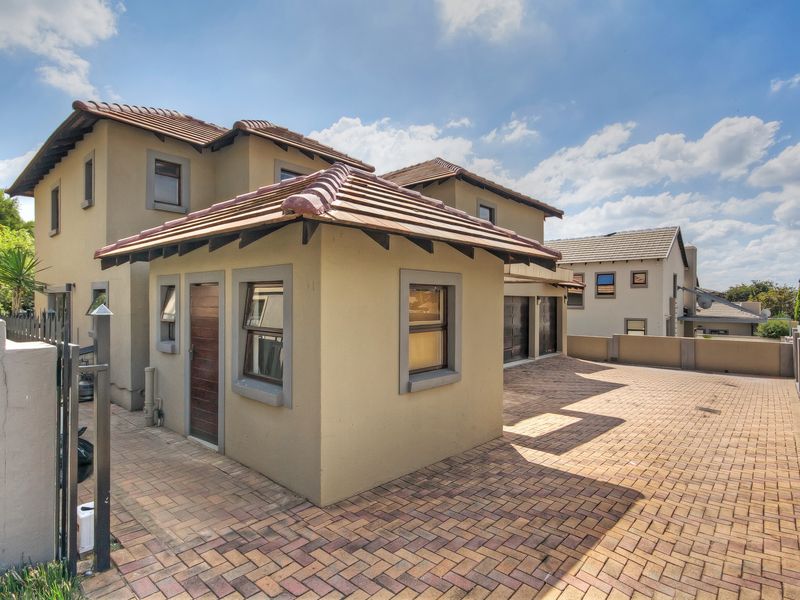 Front view of a multi-story residential property featuring a paved driveway, double garage, and tiled roof architecture.