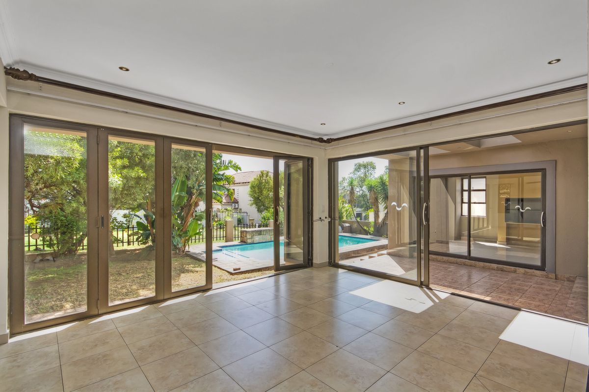 Spacious, light-filled living area featuring large aluminium sliding and folding doors that open onto a covered patio and swimming pool area.