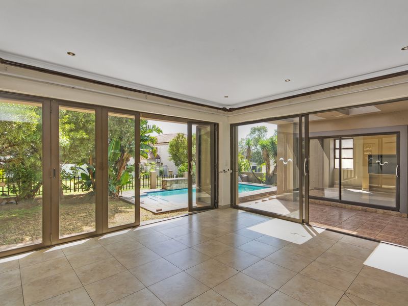 Spacious, light-filled living area featuring large aluminium sliding and folding doors that open onto a covered patio and swimming pool area.