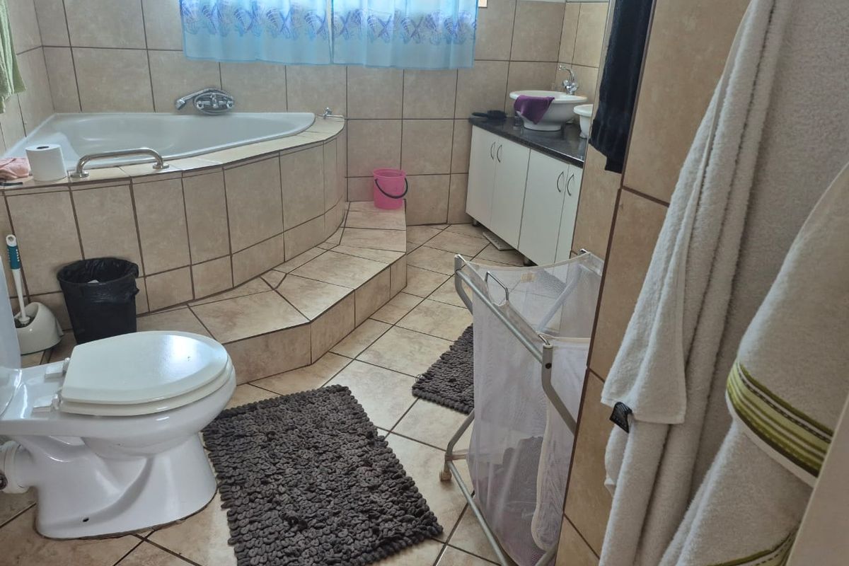 A functional bathroom featuring a corner bathtub with tiled surround, a vanity cabinet with a basin, and a standard toilet.