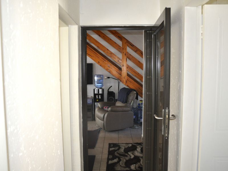 A view through a doorway into a living area featuring exposed timber rafters and tiled flooring.