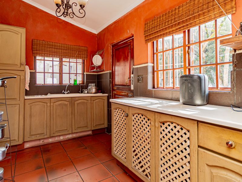 A dated kitchen featuring traditional timber cabinetry, tiled flooring, and a double sink, offering significant potential for a modern renovation.