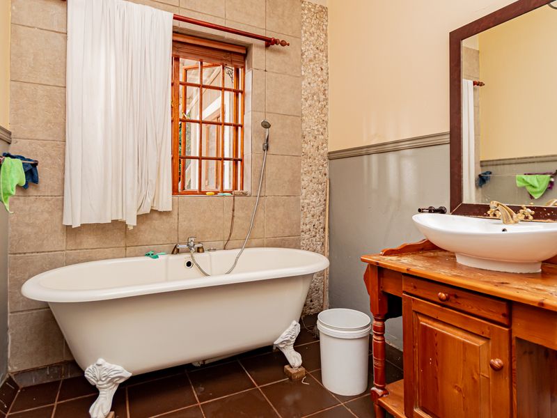 A bathroom featuring a classic clawfoot bathtub, a wooden vanity with a vessel sink, and tiled finishes, offering potential for a modern update.