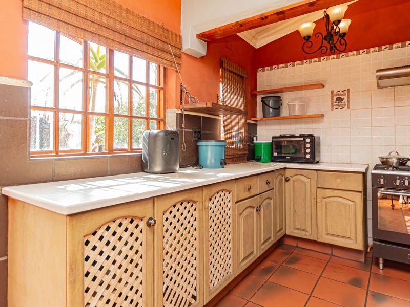 A functional kitchen featuring timber cabinetry, tiled flooring, and a gas stove with an extractor fan, offering a warm, traditional aesthetic.