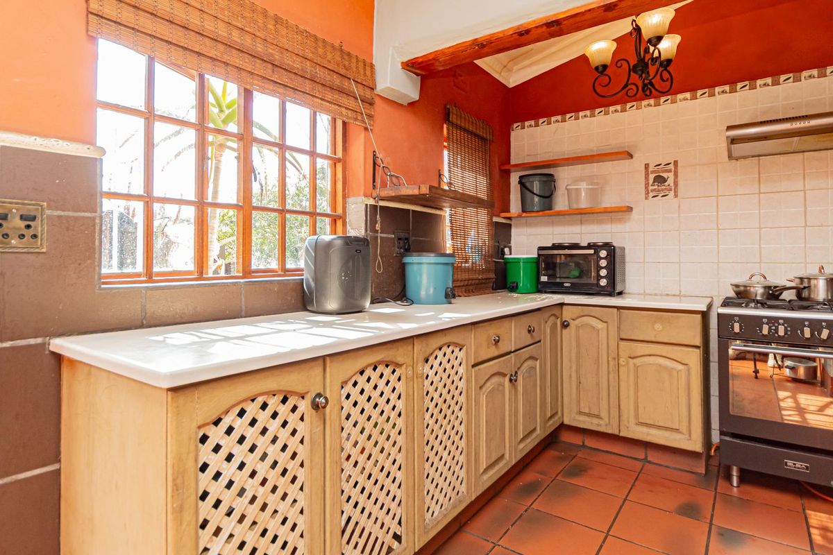 A functional kitchen featuring timber cabinetry, tiled flooring, and a gas stove with an extractor fan, offering a warm, traditional aesthetic.