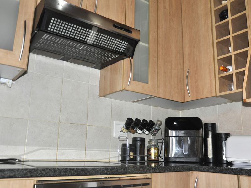 A functional kitchen area featuring laminate cabinetry, granite countertops, a tiled backsplash, and a built-in extractor fan.