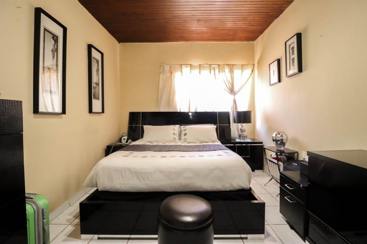 A bedroom featuring a warm timber ceiling and tiled flooring, providing a cozy and functional sleeping space.