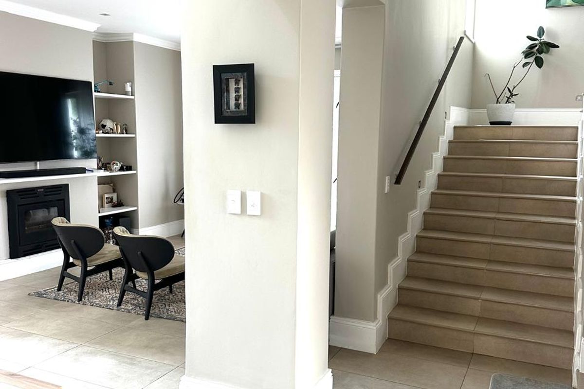 Open plan living area featuring a built-in fireplace, custom shelving, tiled flooring, and a staircase with a modern handrail.