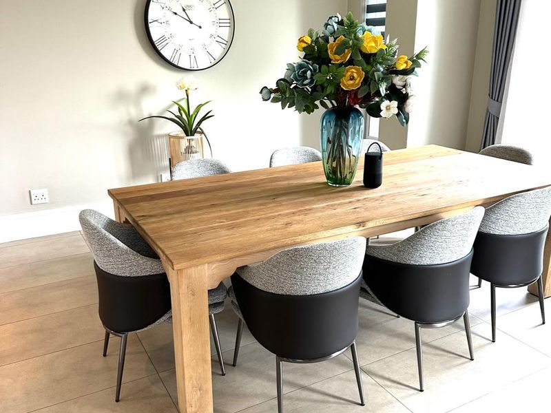 A well-maintained dining area featuring neutral-toned porcelain floor tiles, modern cornice detailing, and a wall-mounted split-system air conditioning unit.