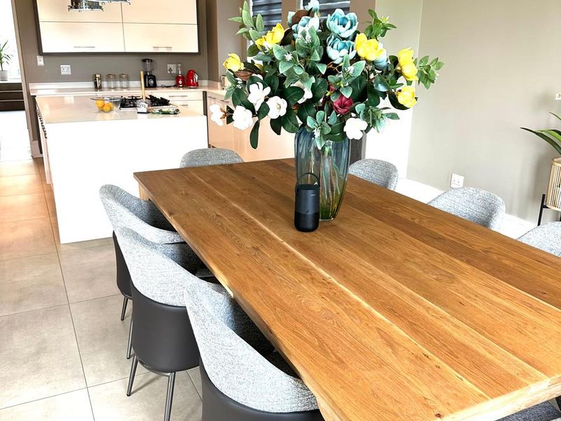 Open-plan dining area featuring tiled flooring and recessed lighting, seamlessly flowing into a modern kitchen with a central island and built-in cabinetry.