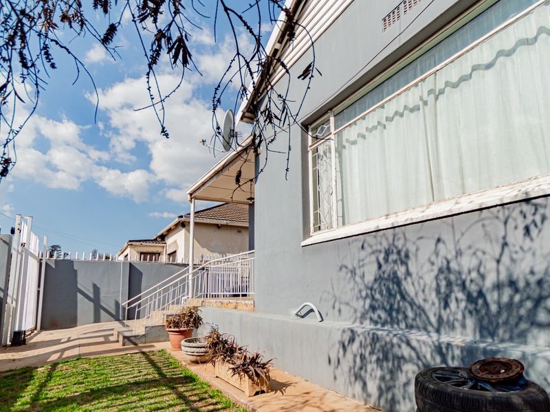 Rear exterior view of the property featuring a concrete patio area, security fencing, and metal staircase access to the building.