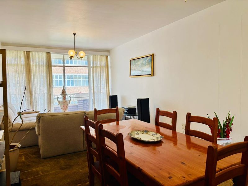 Open plan living and dining area featuring large windows with natural light and a neutral interior palette.