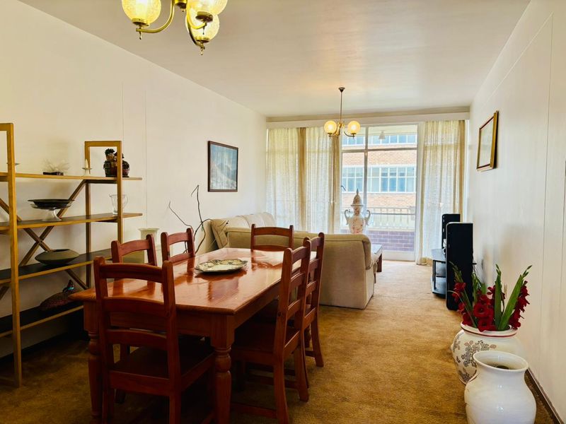 Open plan living and dining area featuring carpeted flooring and large sliding glass doors leading to a private balcony.