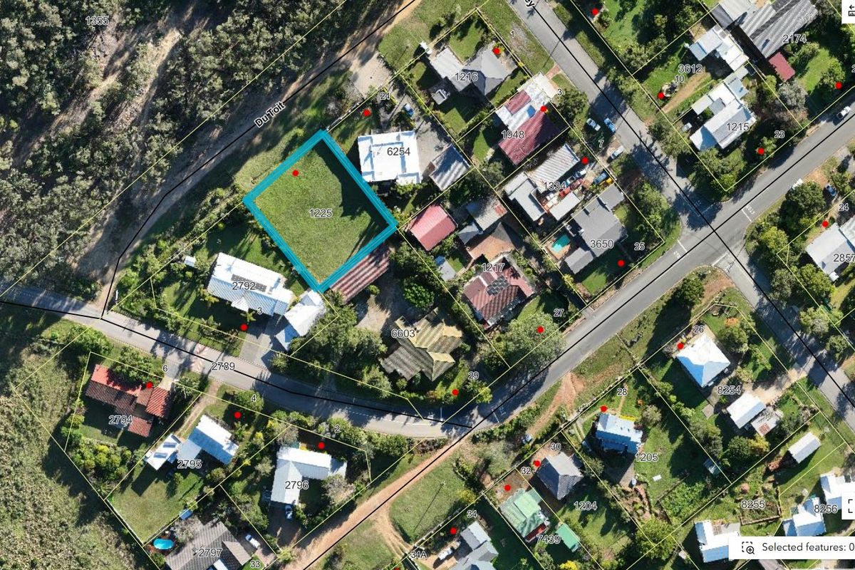 An aerial view of a vacant residential land plot situated within a developed neighborhood.