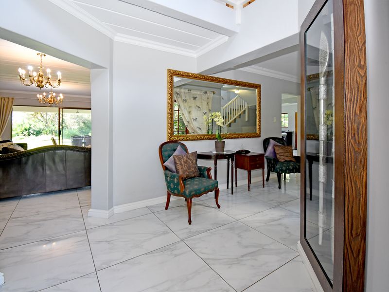 Spacious entrance hall featuring polished marble-look floor tiles, crown molding, and a bright, open-plan layout leading into the living area.