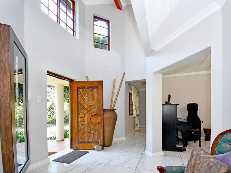 Spacious double-volume entrance hall featuring high ceilings, large windows for natural light, and elegant marble-look floor tiles.