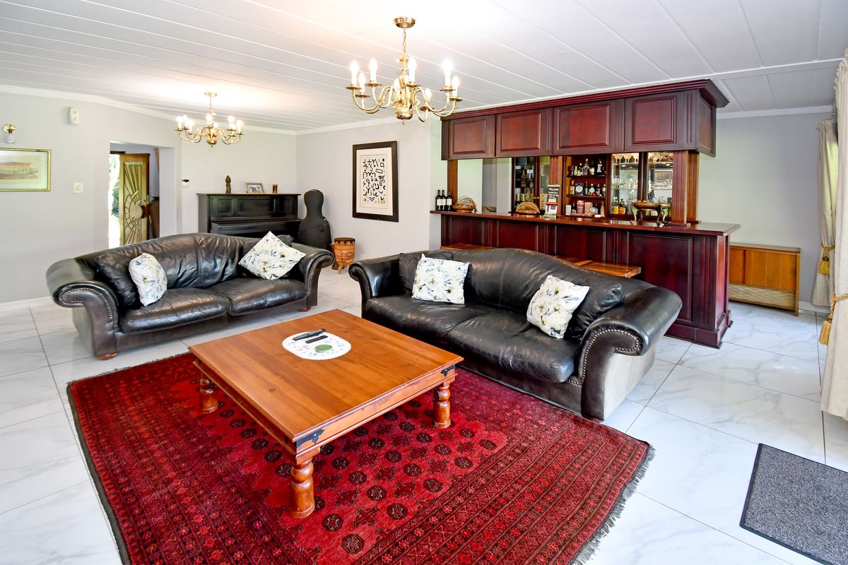 Spacious living room featuring a built-in wooden bar, elegant chandeliers, and polished tiled flooring, creating a comfortable and inviting entertainment space.