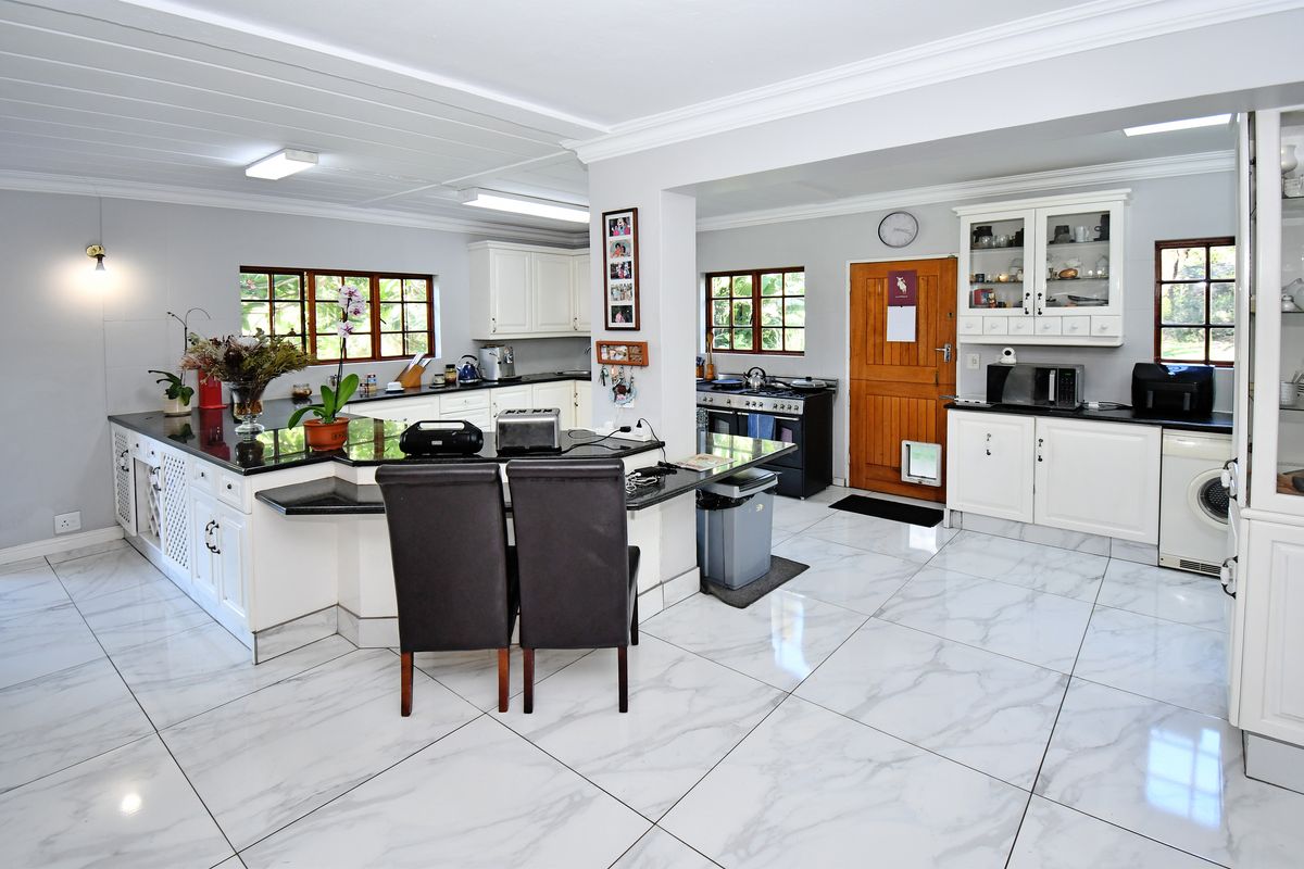 Spacious kitchen featuring white cabinetry, granite countertops, gas stove, and modern marble-look floor tiles, offering a functional layout with ample storage and workspace.