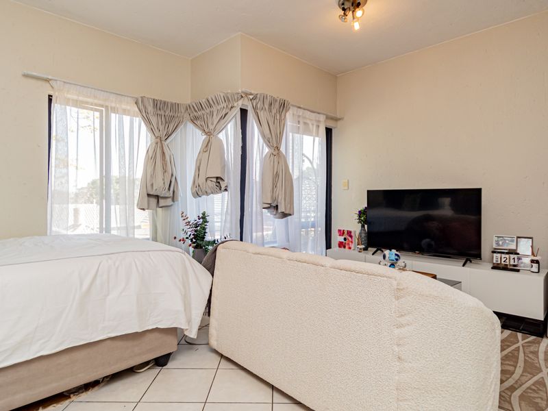 A bedroom featuring tiled flooring and a large sliding glass door that provides natural light.