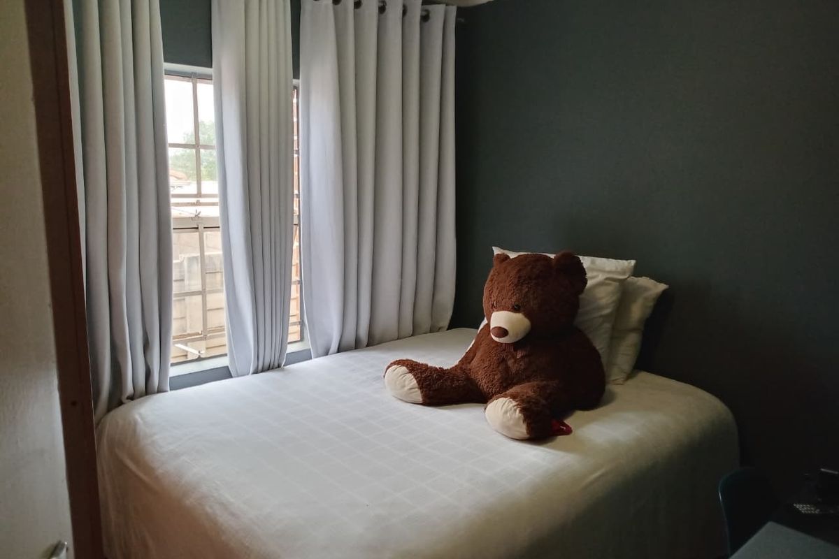 A cozy bedroom featuring dark accent walls and natural light through a window with installed curtain rails.