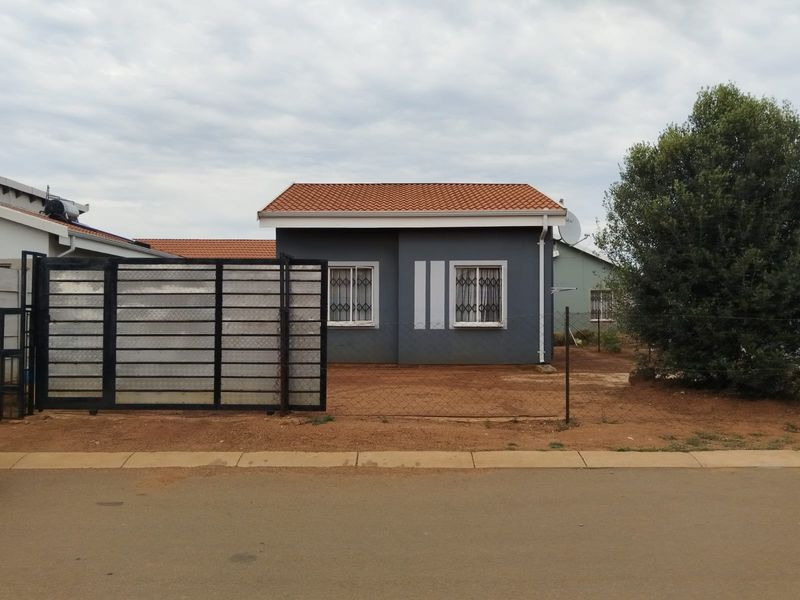 Front exterior view of a detached house featuring a tiled roof, security bars on windows, and a gated entrance.