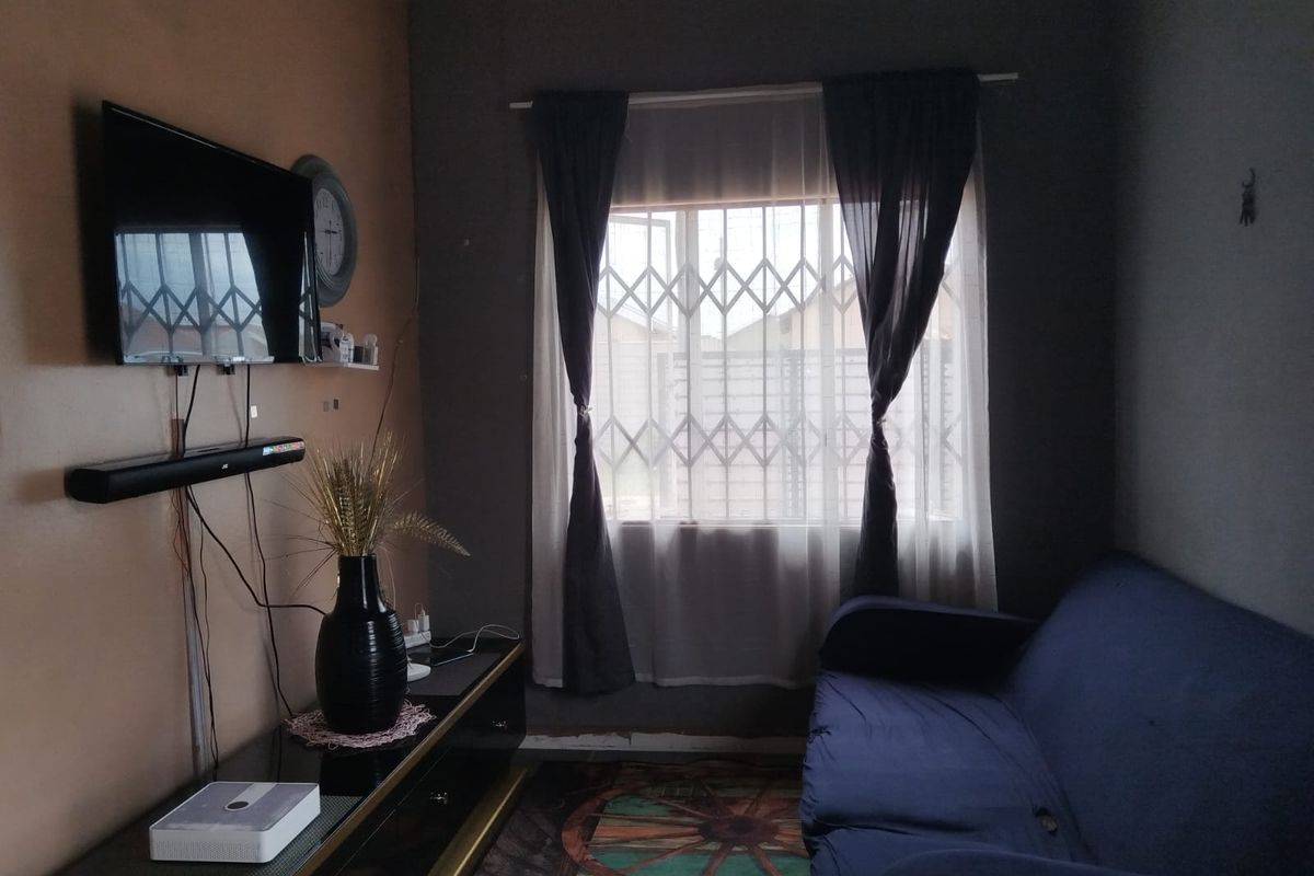 A living room featuring a window with a security gate, requiring minor cosmetic updates and cable management to improve the overall aesthetic.