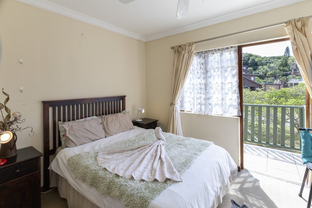 A bedroom featuring a ceiling fan and direct access to a private balcony through a sliding glass door.