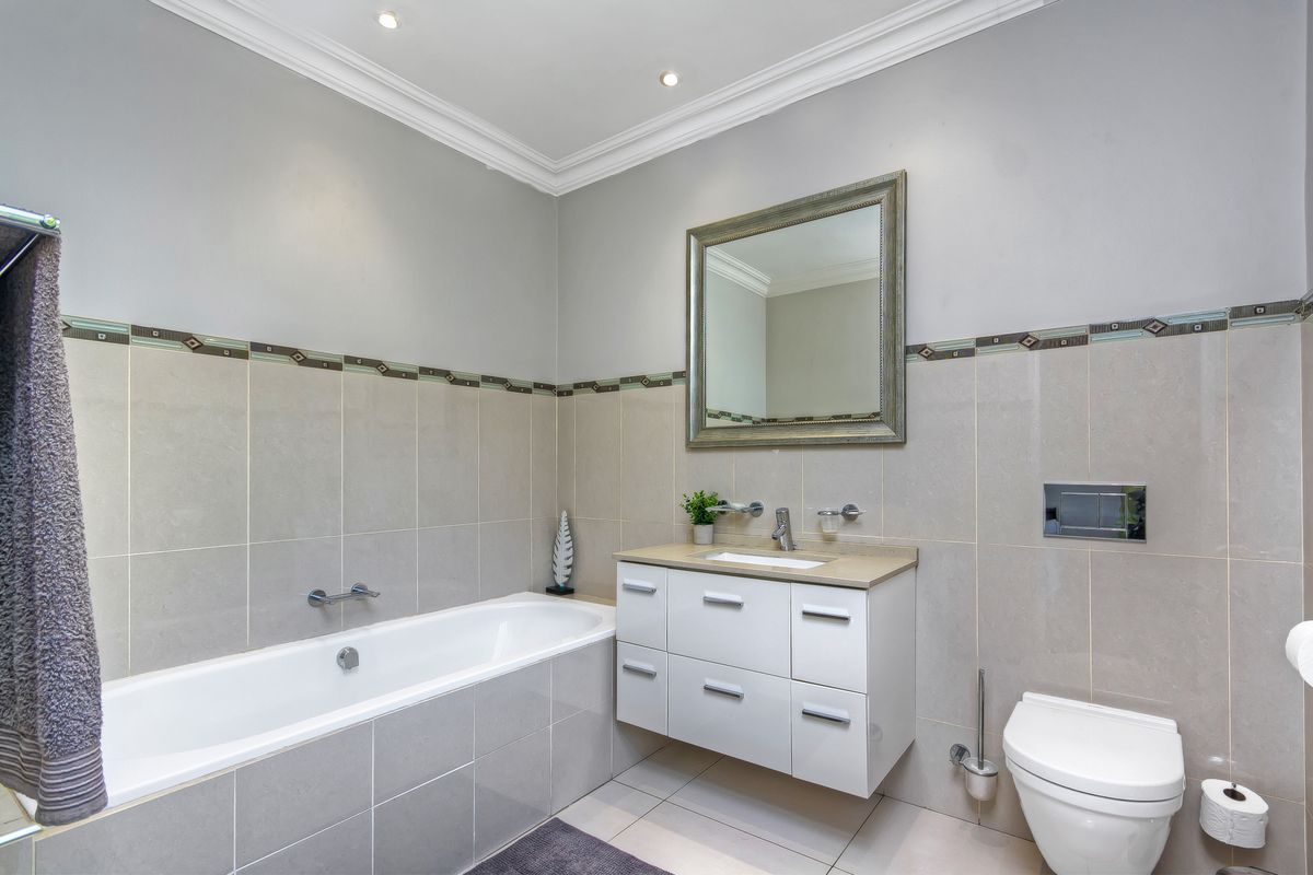 Modern bathroom featuring a built-in bathtub, wall-mounted vanity with integrated basin, and a wall-hung toilet with concealed cistern.