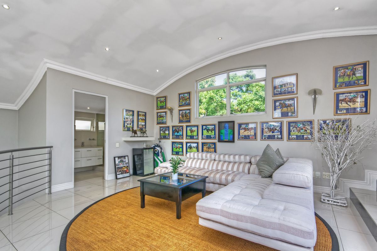 Spacious living area featuring vaulted ceilings, recessed lighting, large arched window, and polished tile flooring, with direct access to an adjacent bathroom.