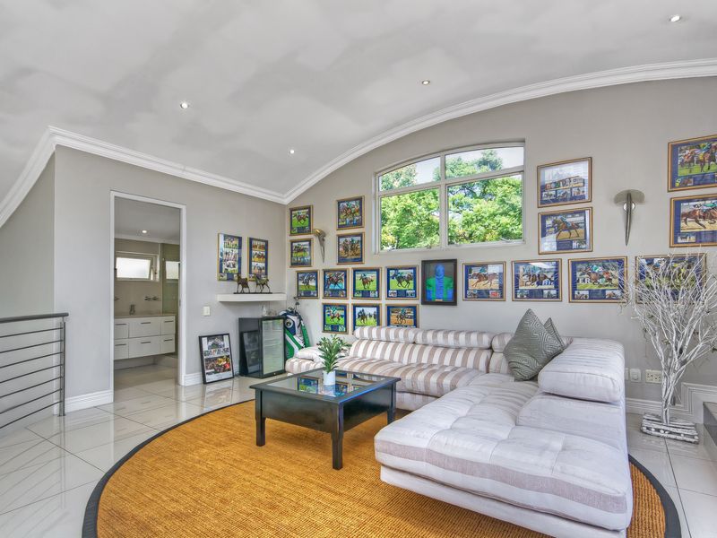 Spacious living area featuring vaulted ceilings, recessed lighting, large arched window, and polished tile flooring, with direct access to an adjacent bathroom.