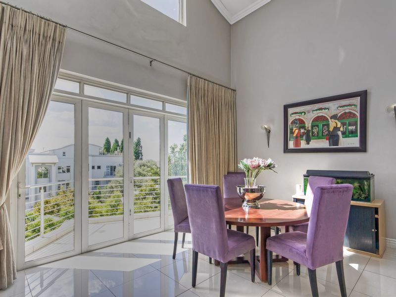 Bright dining area featuring high vaulted ceilings, polished tile flooring, and large glass doors opening onto a private balcony with scenic views.