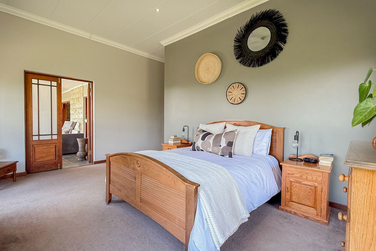 Spacious bedroom featuring neutral wall tones, carpeted flooring, and a classic wooden door leading to an adjacent living area.