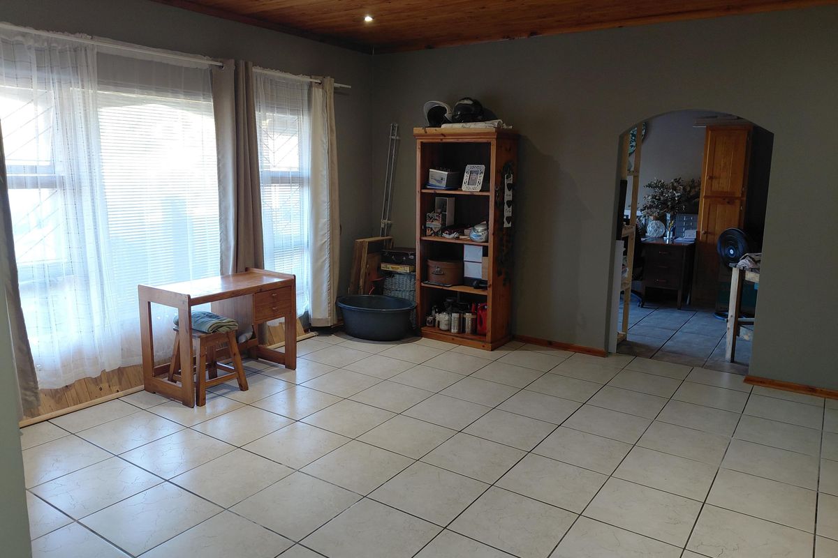 Spacious living area featuring neutral tiled flooring, a timber-paneled ceiling, and an arched doorway leading to an adjacent room.