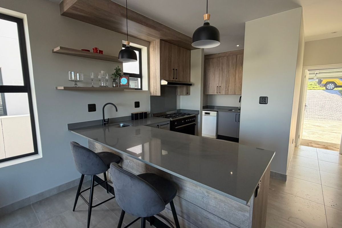Modern kitchen featuring quartz countertops, built-in cabinetry, gas hob, and a breakfast bar, finished with contemporary pendant lighting and tiled flooring.
