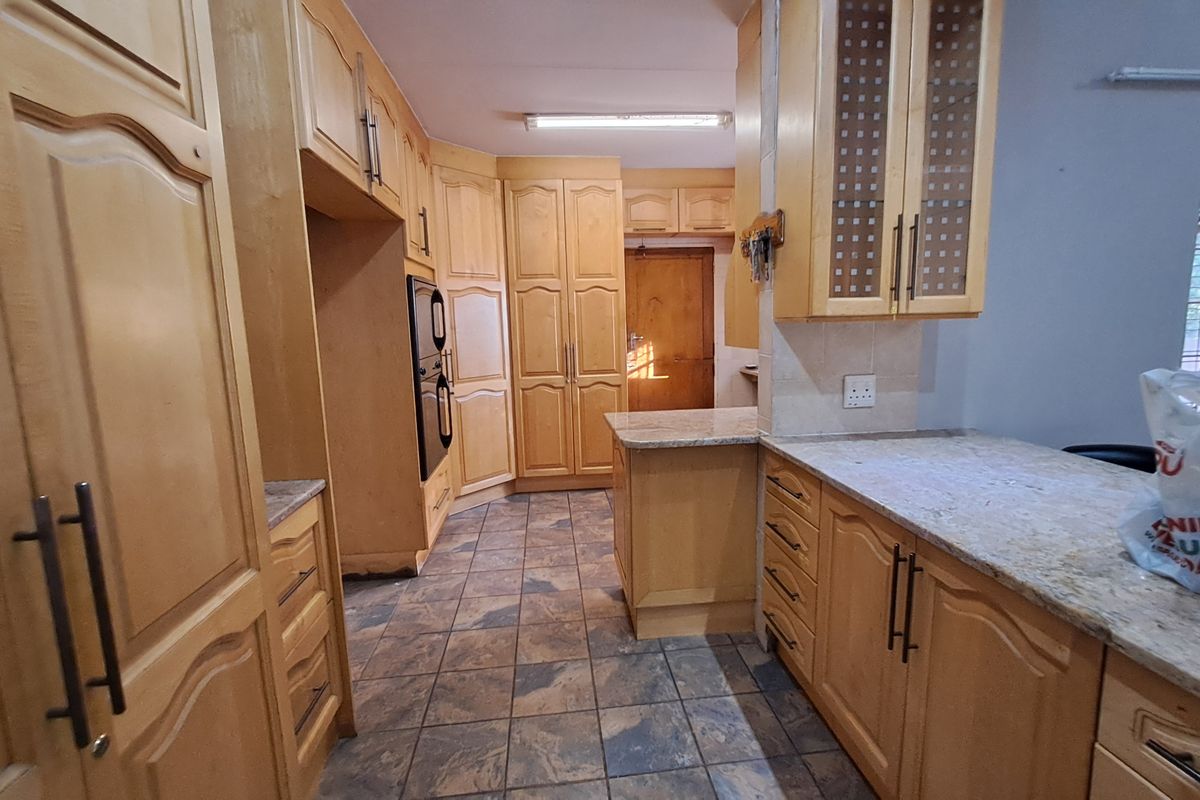 A functional kitchen featuring extensive light wood cabinetry, granite countertops, and tiled flooring, offering ample storage and workspace.